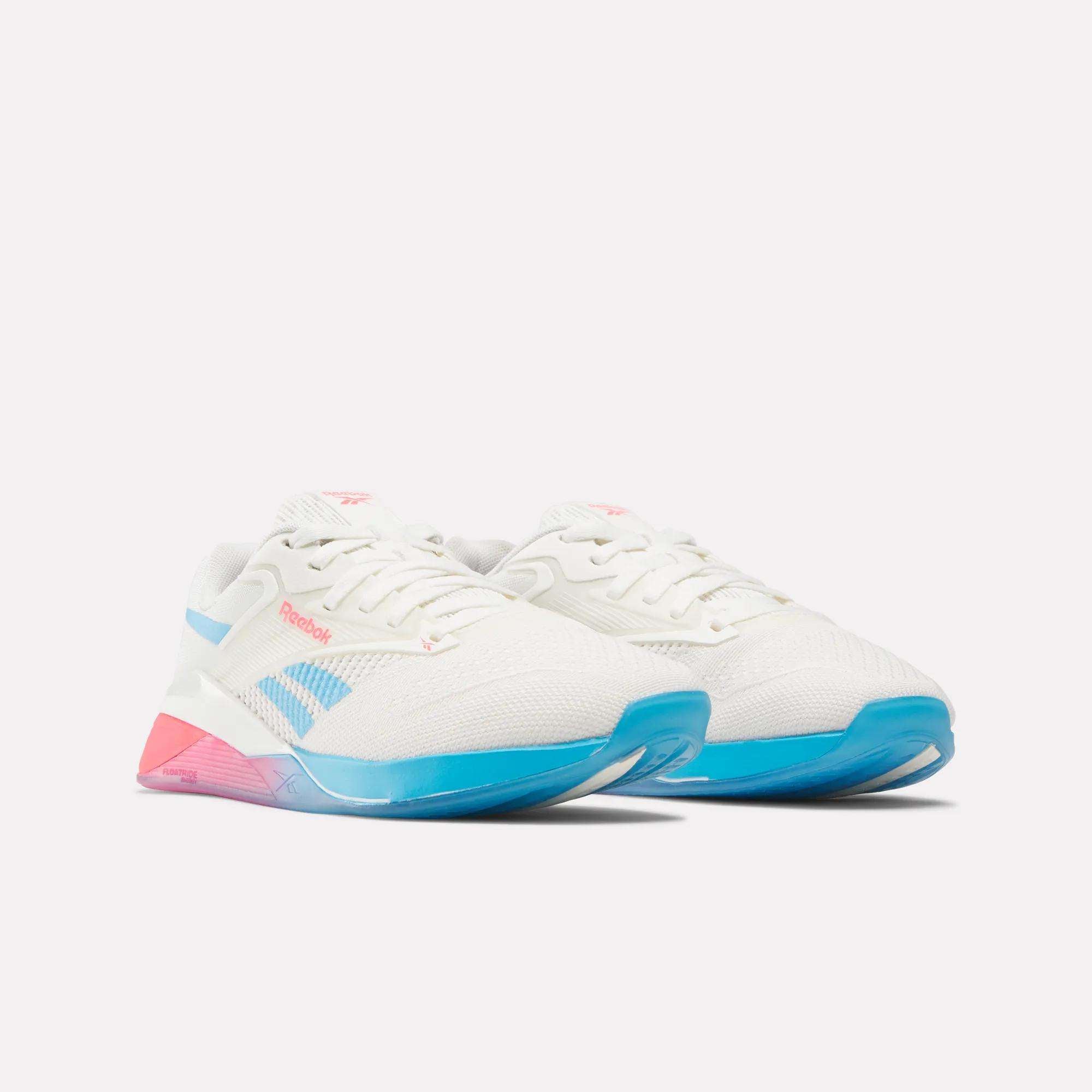 Women's Reebok Nano X4 Training Shoes in white with blue and pink accents are shown on a plain white background. These lightweight trainers offer everyday comfort for your workouts.