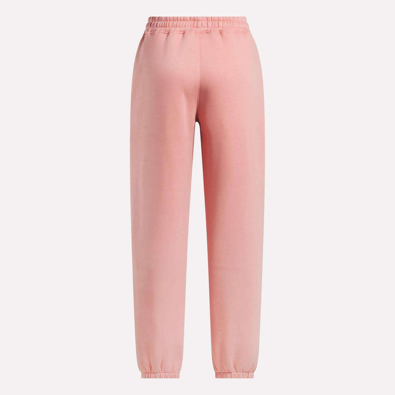 The Reebok Women's Wardrobe Essentials Sweat Pants in light pink feature an elastic waistband, ankle cuffs, and soft fleece material, shown against a plain white background.