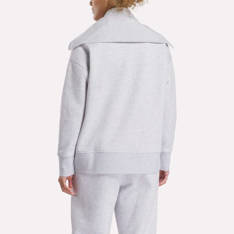 A person is shown from the back against a plain light background, wearing a light gray Reebok Women's Wardrobe Essentials Retro Zip Top with a wide collar and matching sweatpants.