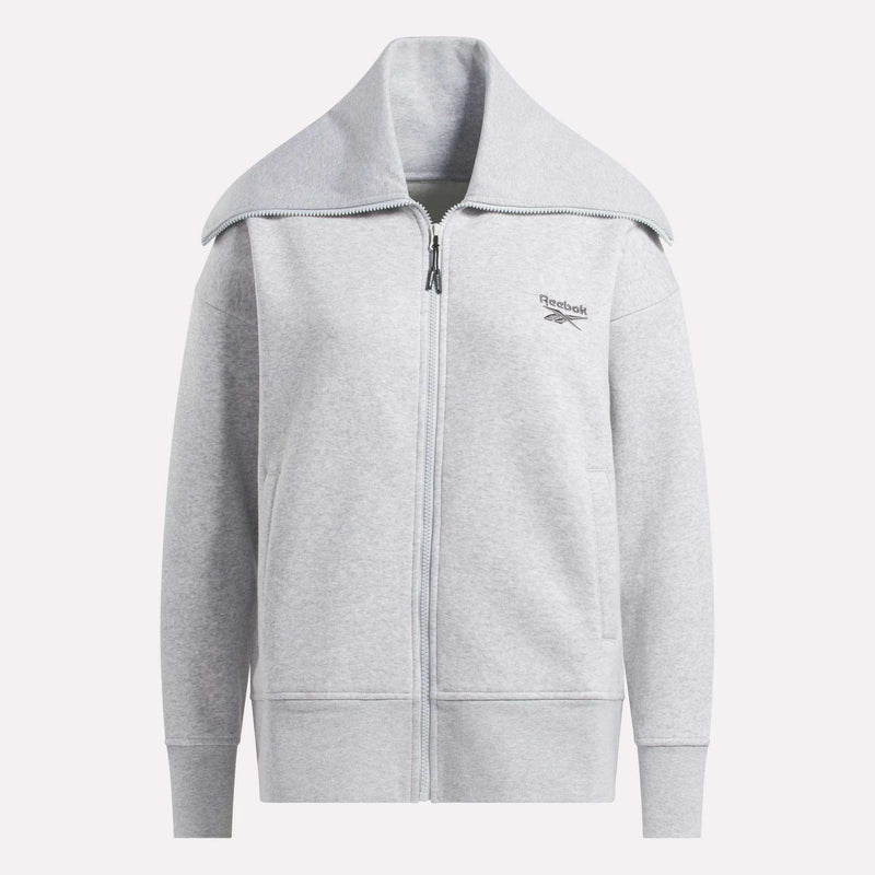 The Reebok Women's Wardrobe Essentials Retro Zip Top is a light gray fleece sweatshirt with a wide collar, long sleeves, and a minimalistic design. It features the Reebok logo on the left chest. Shown against a plain white background.