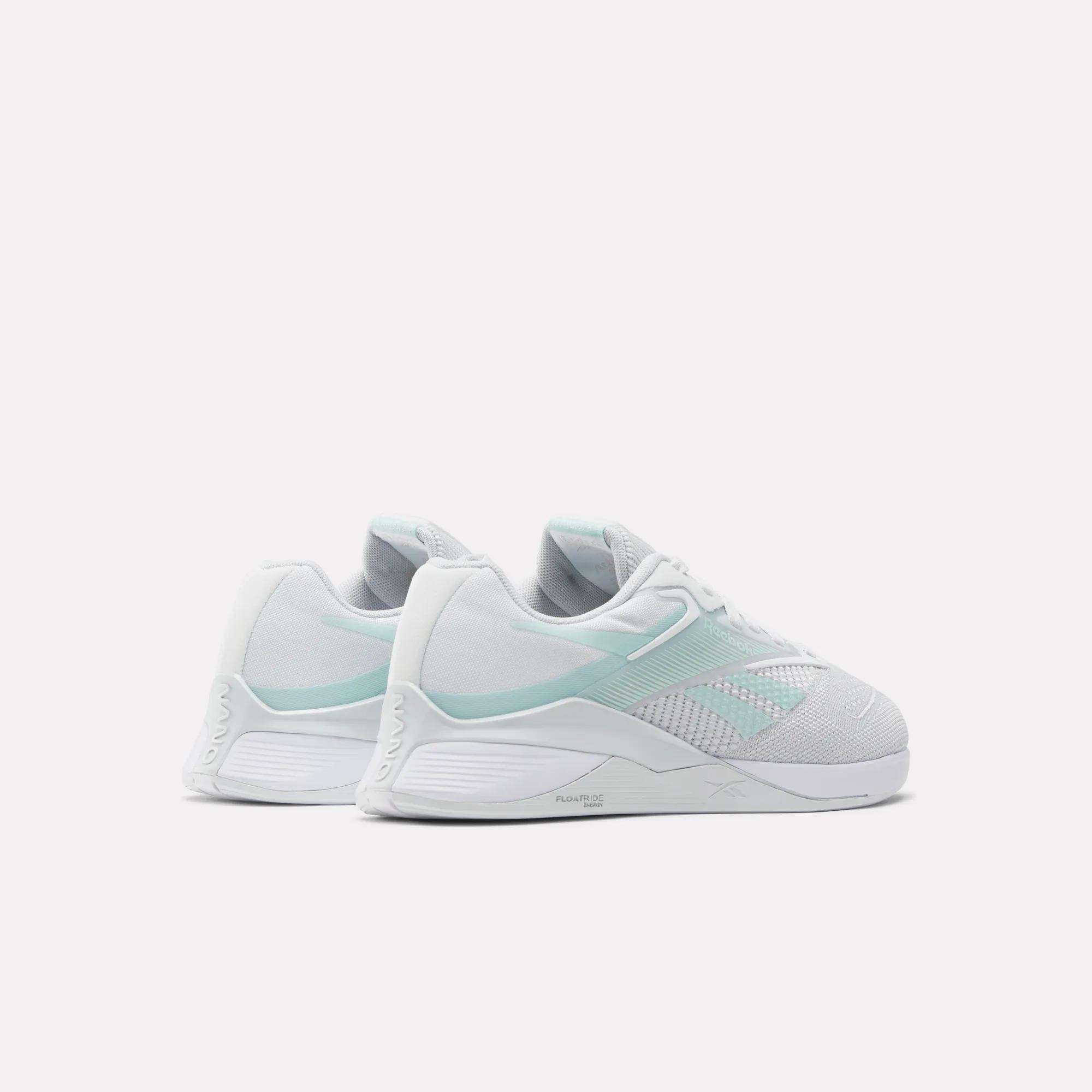 A pair of Reebok Women's Nano X4 Training Shoes in white and pale mint green with Floatride Energy Foam are shown side by side on a light background, displaying their sides and backs.