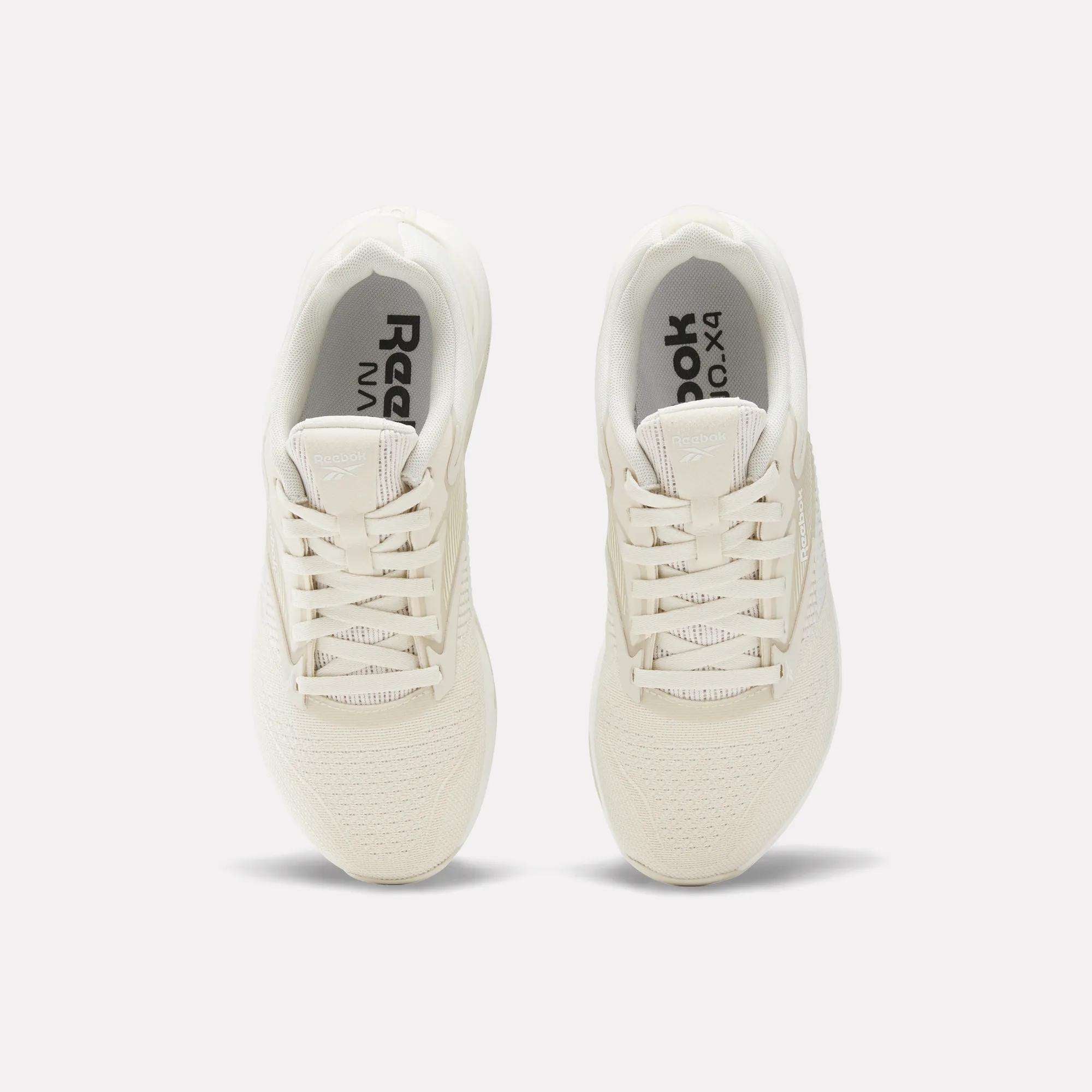 Top view of a pair of off-white Women's Nano X4 Training Shoes by Reebok with laces and a Flexweave upper, displayed side by side on a plain white background.