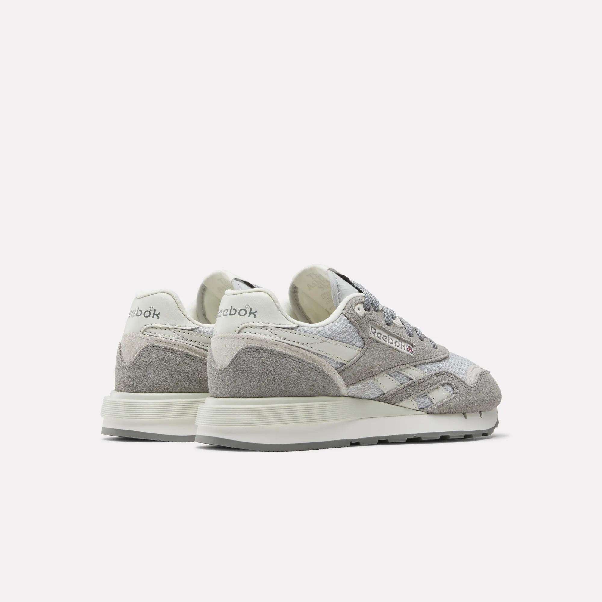 The Reebok Women's Classic Nylon 89 Shoes, shown in grey and white suede and mesh with retro styling, feature the Reebok logo on the heel and side, displayed from back and side angles.