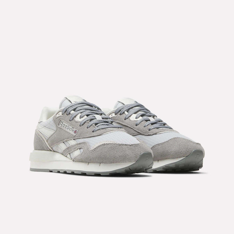 The Reebok Women's Classic Nylon 89 Shoes feature a retro design in light gray and white with suede and mesh panels, white midsoles, and gray outsoles, shown against a plain white background.