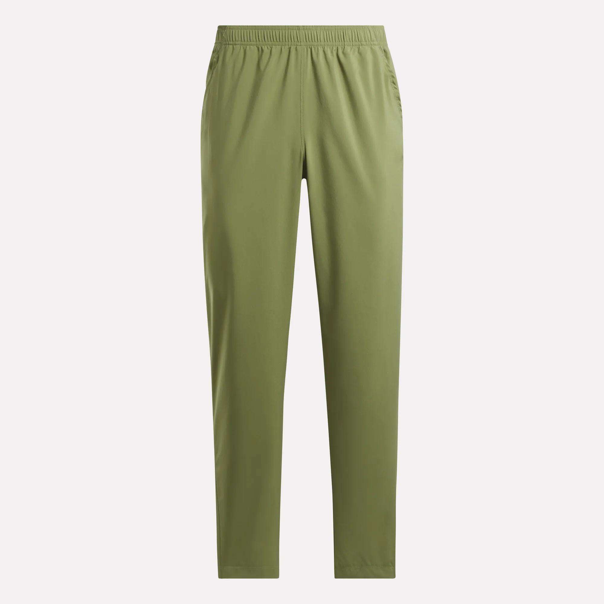 The Reebok Men's Train Woven Unlined Pants are olive green, straight-leg workout pants with an elastic waistband and side pockets, made from lightweight fabric and shown against a plain light background.