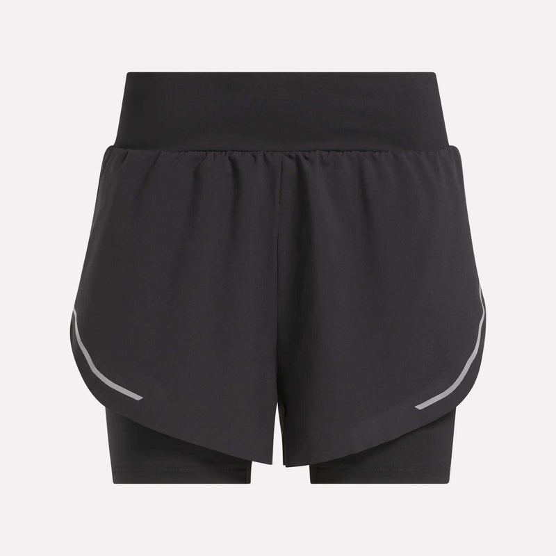 The Reebok Women's Lux Metallic 2-in-1 Running Shorts 3" are black, high-waisted shorts with an overlapping front layer, reflective curved side stripes, and fitted inner shorts. Shown against a plain light gray background.