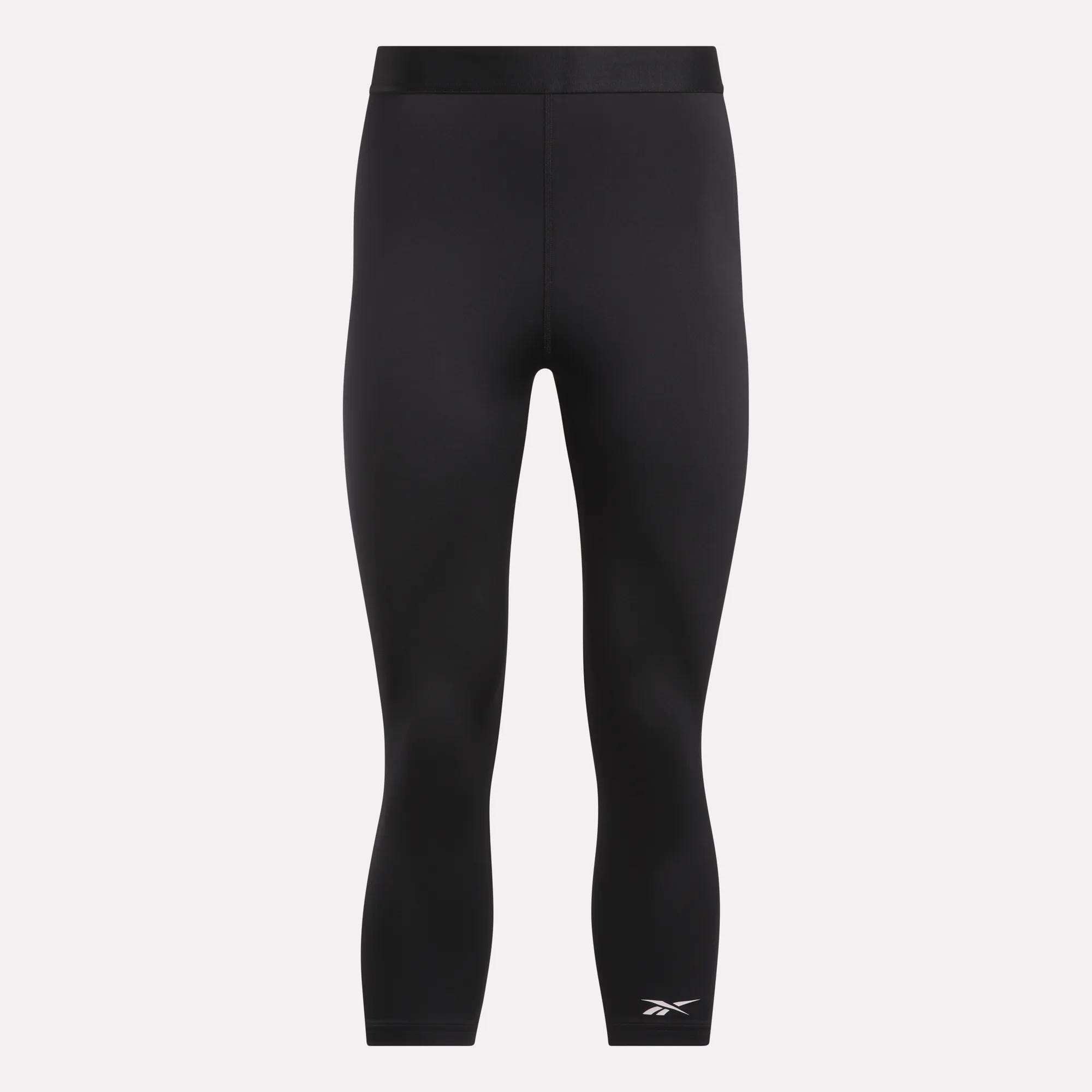 Reebok Women's ID Basketball 3/4 Compression Leggings feature a mid-rise waistband, three-quarter length, and a white logo on the lower left leg. Made from moisture-wicking fabric for comfort. Displayed on a plain light background.