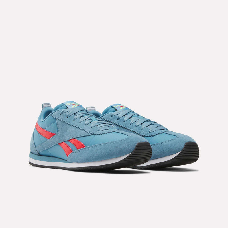 A pair of Reebok R100 Shoes in blue with red accents and black soles, shown on a white background. These low-profile sneakers feature retro '70s running style, classic branding, and matching blue laces for a timeless look.