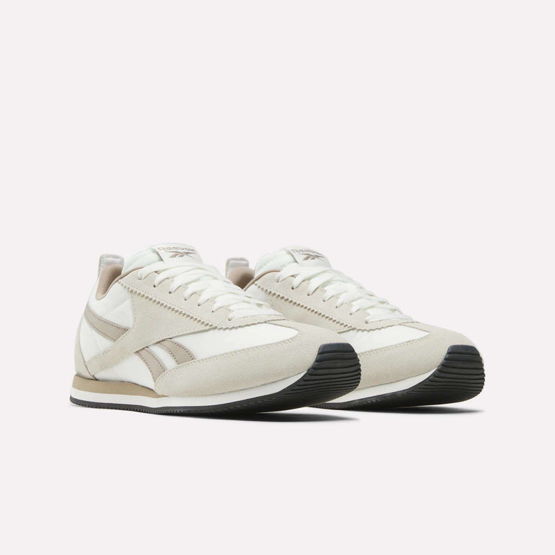 A pair of Reebok R100 Shoes in off-white with beige accents, white laces, and black rubber soles is shown on a plain white background, offering a timeless '70s running-inspired style.