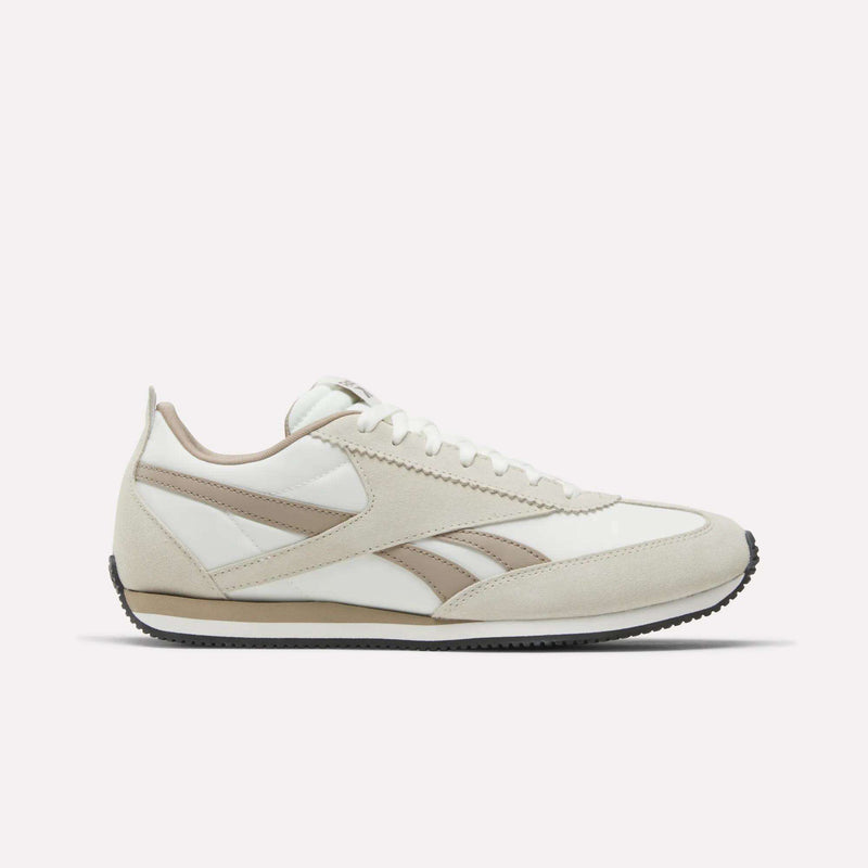 The Reebok R100 Shoes feature a white and beige suede and leather upper, beige side stripes, white laces, and a black rubber sole, displayed in profile on a plain white background for classic '70s running style.