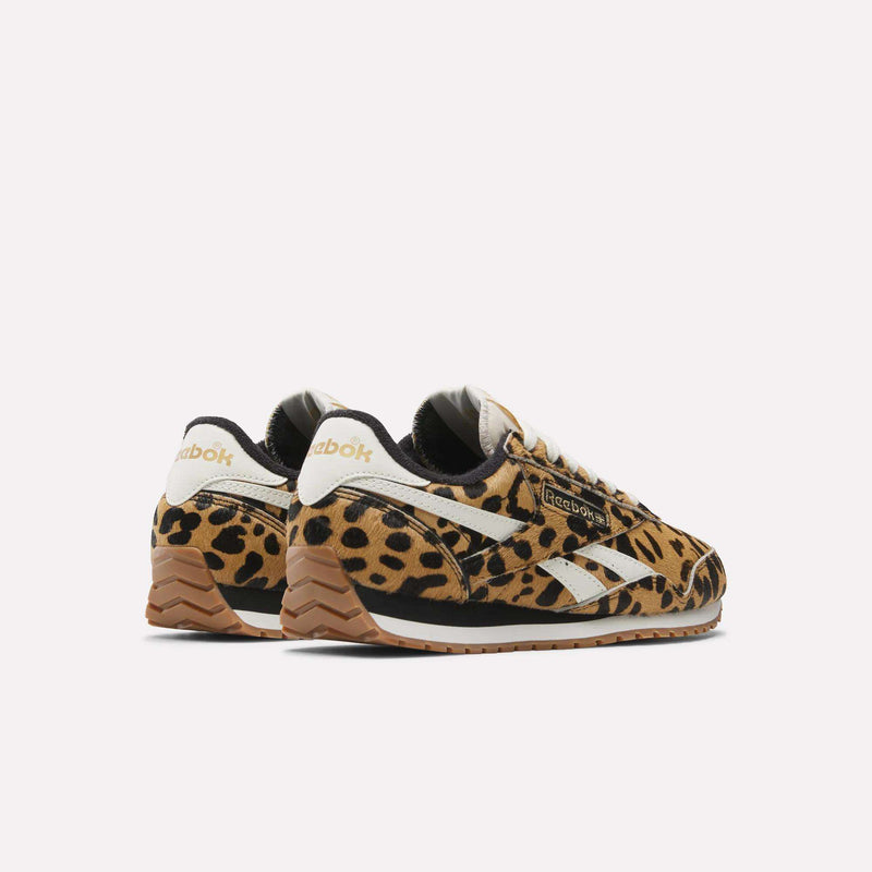 A pair of Reebok Women's Classic AZ Shoes featuring a brown, black, and tan animal print, white side stripes, and tan outsoles is displayed against a plain white background.