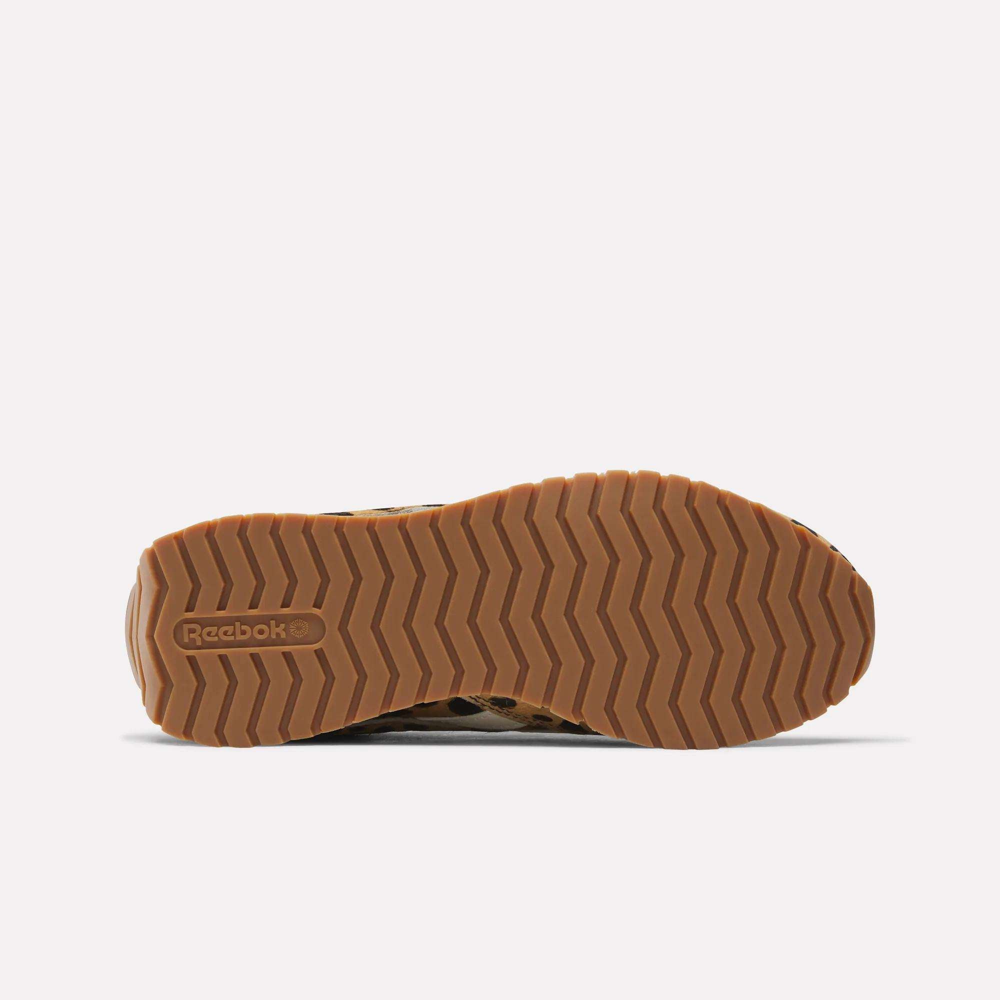 The image shows the bottom view of Reebok Women's Classic AZ Shoes, featuring a brown rubber sole with a herringbone tread and the Reebok logo embossed on the left side. The background is plain white.