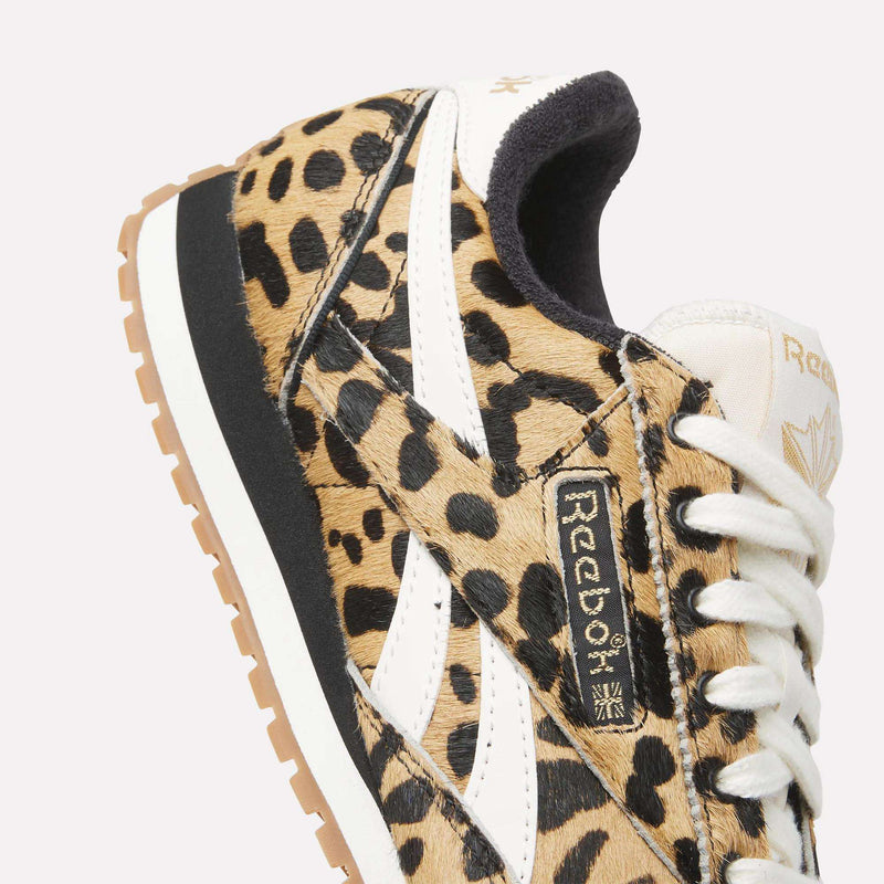 Close-up of Reebok Women's Classic AZ Shoes featuring a tan and black animal print, white side stripes, beige laces, and light brown sole with gold Reebok logo—perfect statement sneakers.