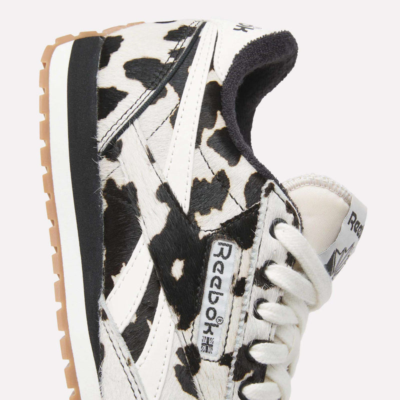 Close-up of Reebok Women's Classic AZ Shoes with a striking black and white animal print, white laces, beige sole, and prominent Reebok logo on the side and tongue.