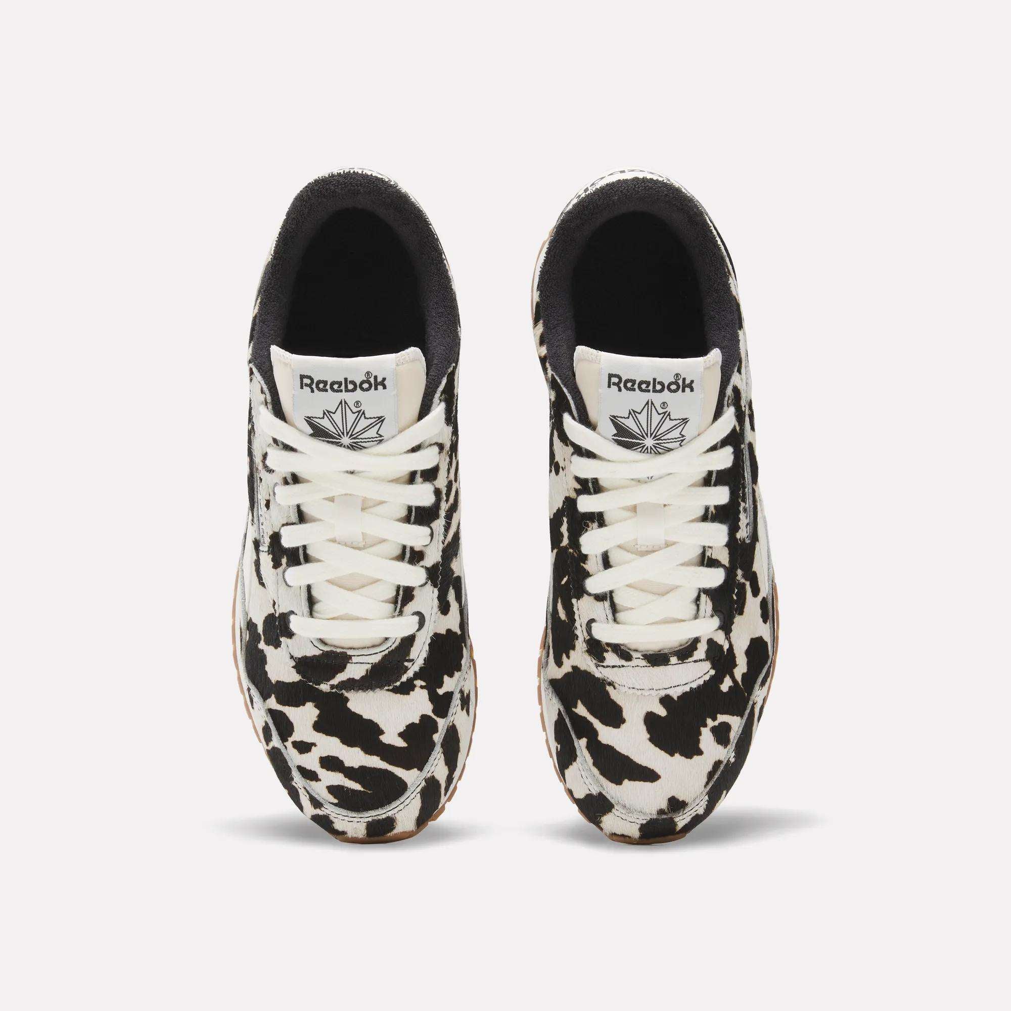 A top view of the Reebok Women's Classic AZ Shoes, featuring white laces and a striking black and white animal print pattern.