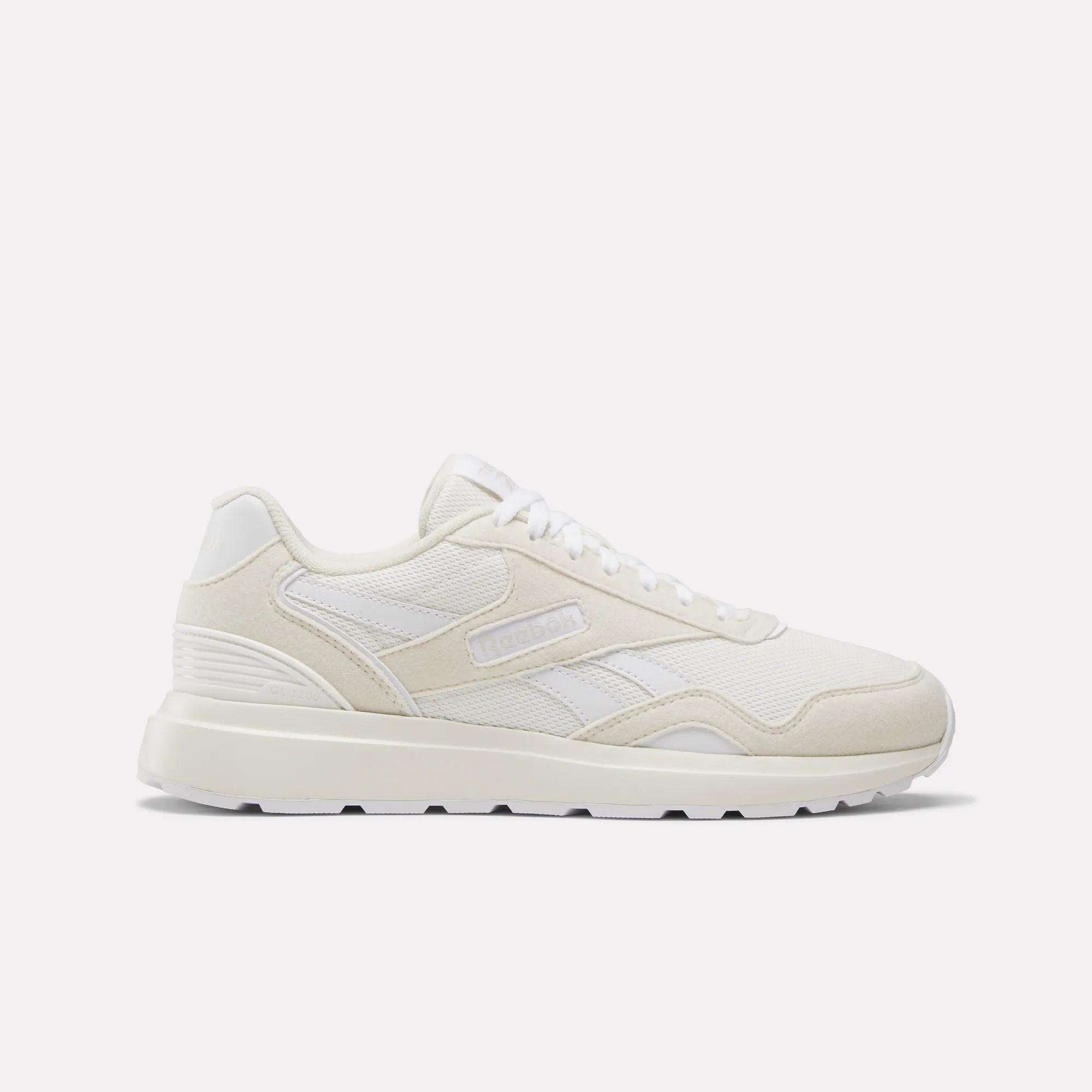 The Women's GL1100 Shoes by Reebok are white athletic sneakers with side stripes, a textured sole, and subtle branding, shown in profile on a plain white background—perfect for comfortable everyday wear.