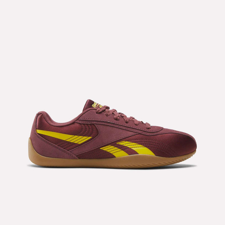The Reebok Women's Ultra Lo Shoes feature a maroon upper with yellow branding and accents, lightweight construction, a low-profile lace-up design, and a gum sole—all displayed on a plain white background.