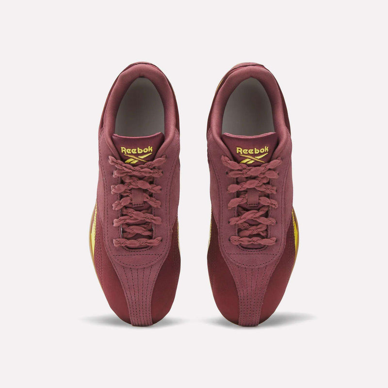 A pair of Reebok Women's Ultra Lo Shoes in maroon with gold accents is shown from above, highlighting the tops, laces, and Reebok logo on the tongues. These lightweight sneakers are displayed against a crisp white background.