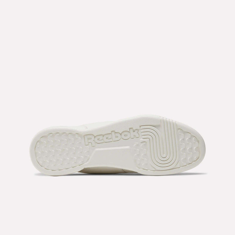 The image displays the white rubber sole of the Reebok Workout Plus Shoes, with a central Reebok logo and both circular and linear treads inspired by classic '80s fitness style for added traction.