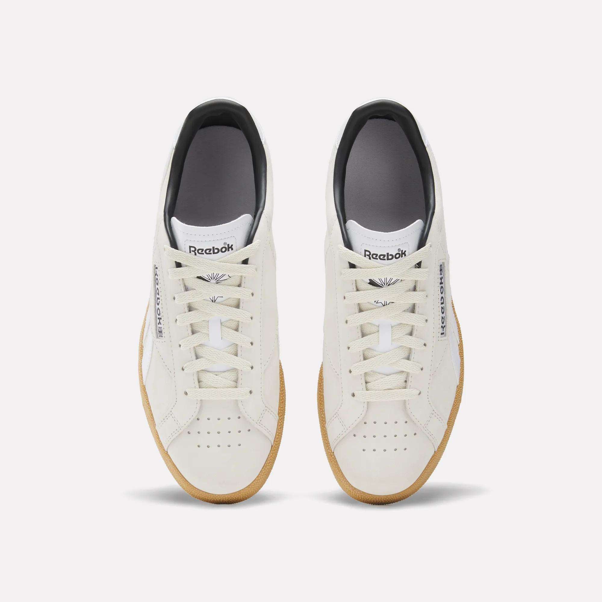 A top view of the Reebok Club C Grounds UK Shoes in white with beige soles. These sneakers feature white laces, perforated toe boxes, and the Reebok logo on both tongue and side for a classic look.
