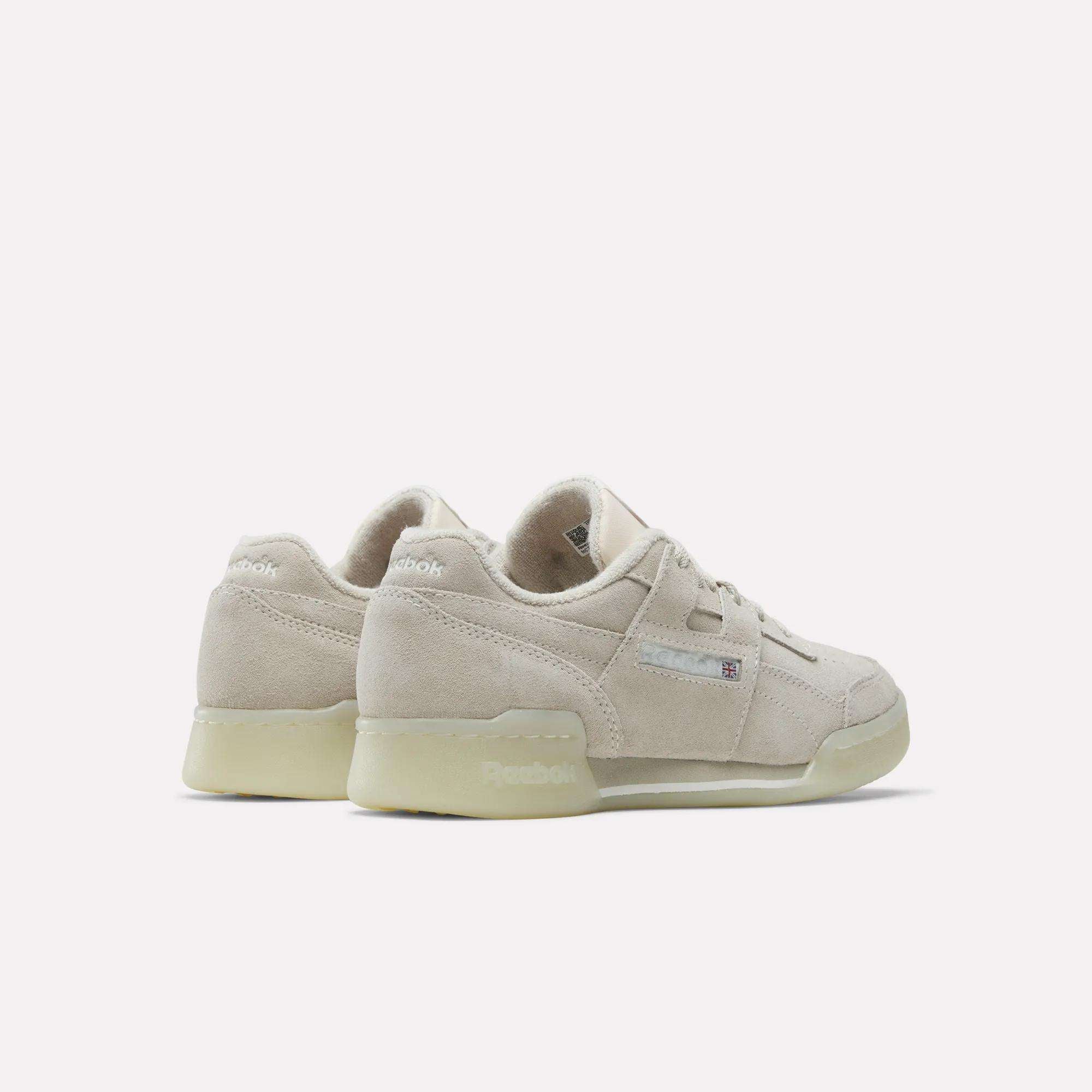 Beige Reebok Women's Workout Plus Shoes with suede texture, low tops, and translucent off-white soles reflect '80s fitness style. One shoe shows the side view; the other highlights the back heel.