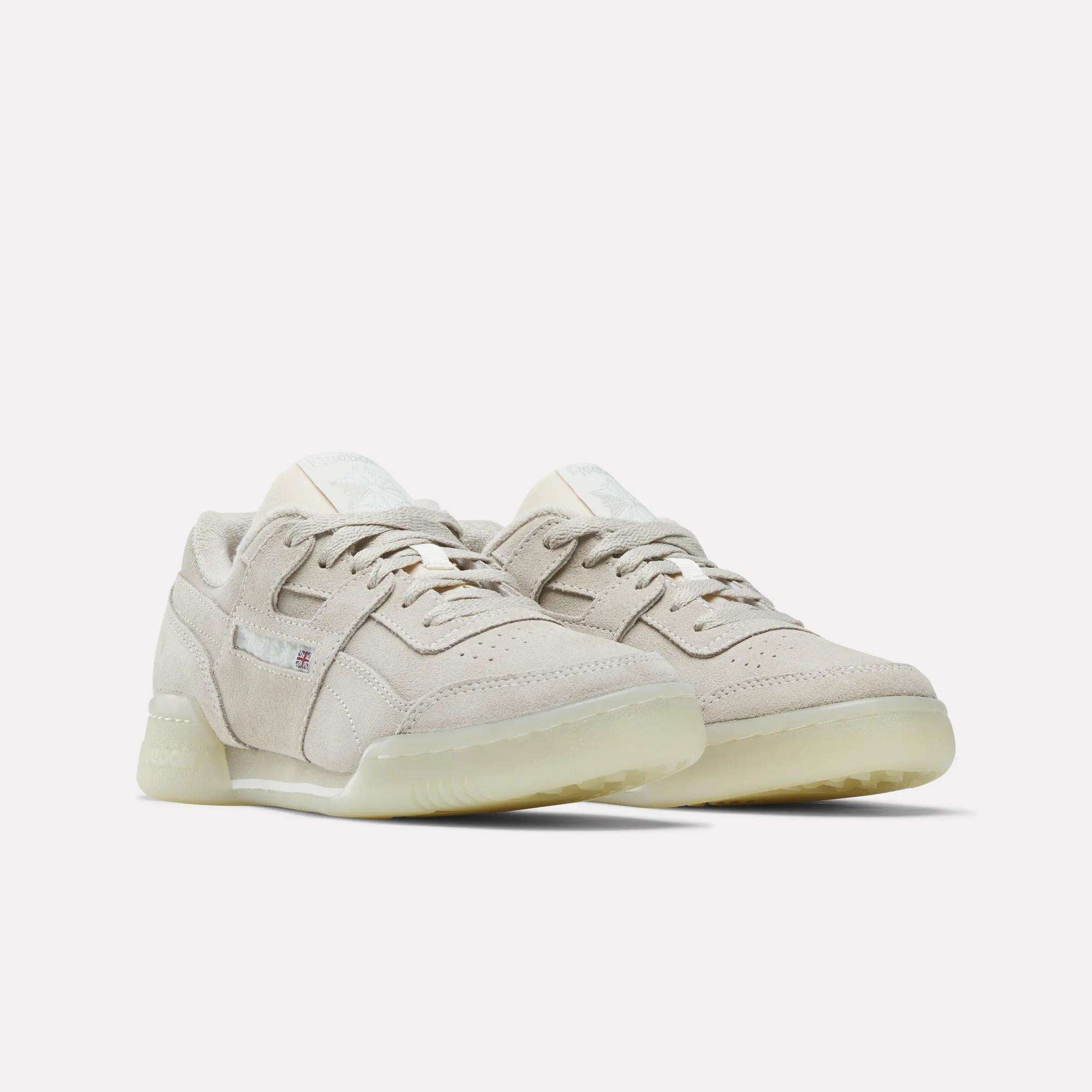 A pair of Women's Workout Plus Shoes by Reebok in beige suede with translucent off-white soles, inspired by '80s fitness style, displayed against a plain white background.