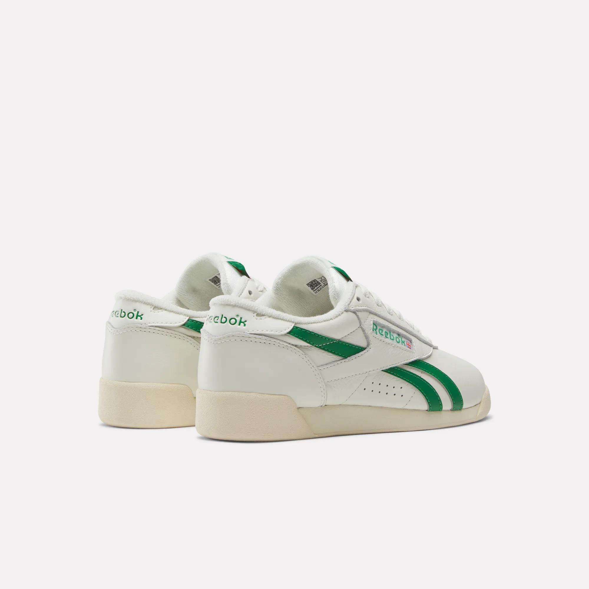 The Women's Freestyle Lo Shoes by Reebok feature white leather with green stripes and accents, an EVA midsole, and are shown from the back and side on a plain white background.