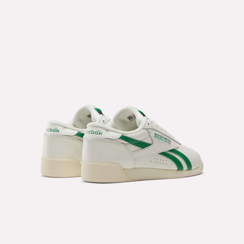 The Women's Freestyle Lo Shoes by Reebok feature white leather with green stripes and accents, an EVA midsole, and are shown from the back and side on a plain white background.