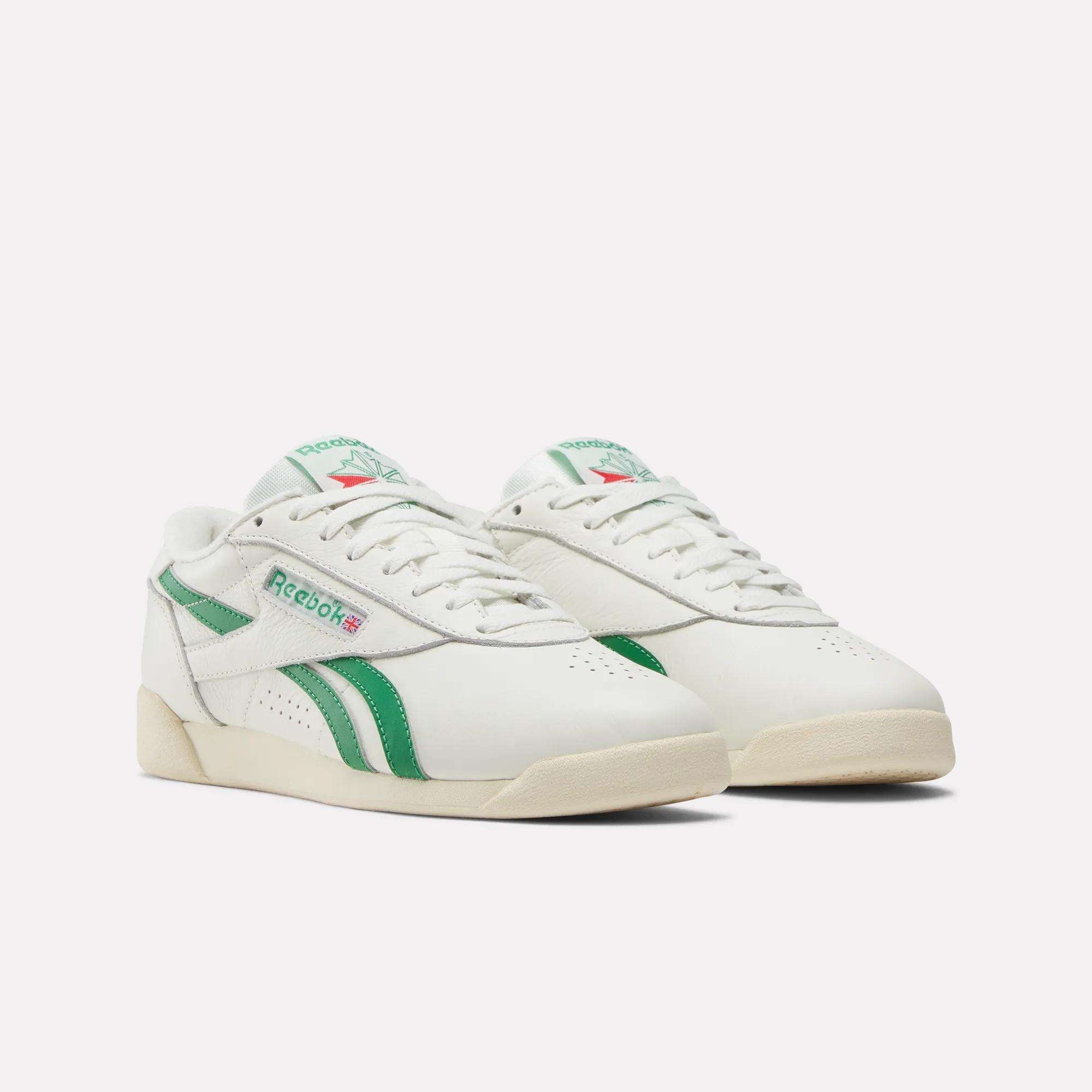 The Reebok Women's Freestyle Lo Shoes feature green accents and stripes, classic retro design, leather uppers, an EVA midsole for comfort, off-white soles, and a green Reebok logo on the sides for stylish flair.