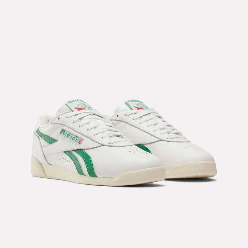 The Reebok Women's Freestyle Lo Shoes feature green accents and stripes, classic retro design, leather uppers, an EVA midsole for comfort, off-white soles, and a green Reebok logo on the sides for stylish flair.