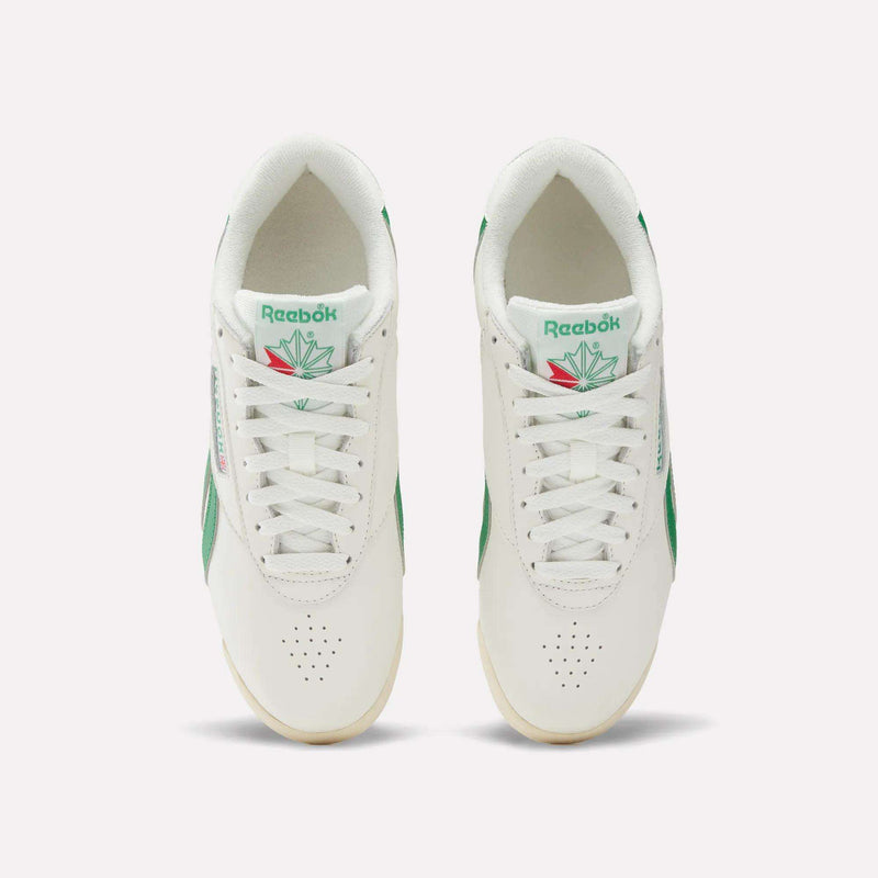 Top view of Reebok Women's Freestyle Lo Shoes in white leather with green accents, white laces, and a tongue logo featuring green and red. Set on a light background. EVA midsole offers extra comfort.