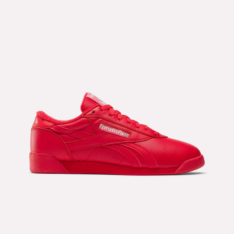 The Reebok Women's Freestyle Lo Shoes, shown in vibrant red from a side view on a white background, highlight the classic Reebok logo and signature stitching as part of the women's shoe collection.