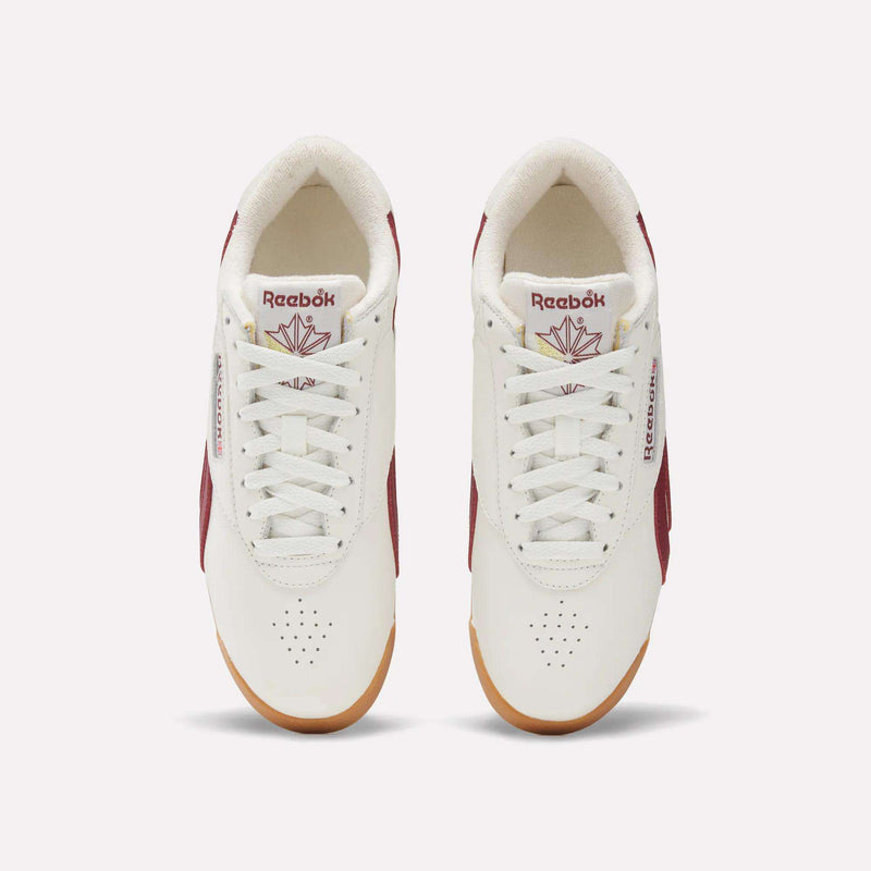 Top view of Women's Freestyle Lo Shoes by Reebok in white with maroon accents, gum soles, and logo with red maple leaf on the tongue. These women's retro sneakers are neatly laced and set side by side on a light background.