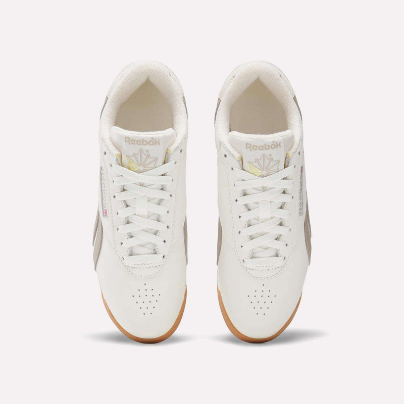 A pair of Women's Freestyle Lo Shoes by Reebok with white uppers, beige side panels, and gum soles is viewed from above on a plain light background. The Reebok logo appears on the tongues and sides of these classic sneakers.