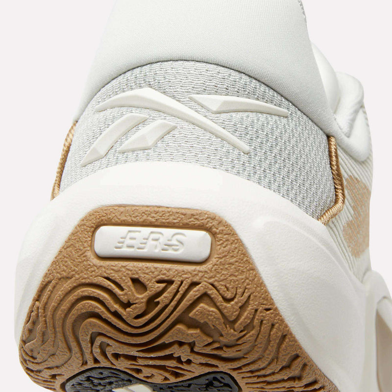 Close-up of the back of a white and gray Reebok Engine A 26 Basketball Shoe, designed for stability, with the Reebok logo on the heel and a textured brown rubber outsole featuring E.R.S embossed above the sole.