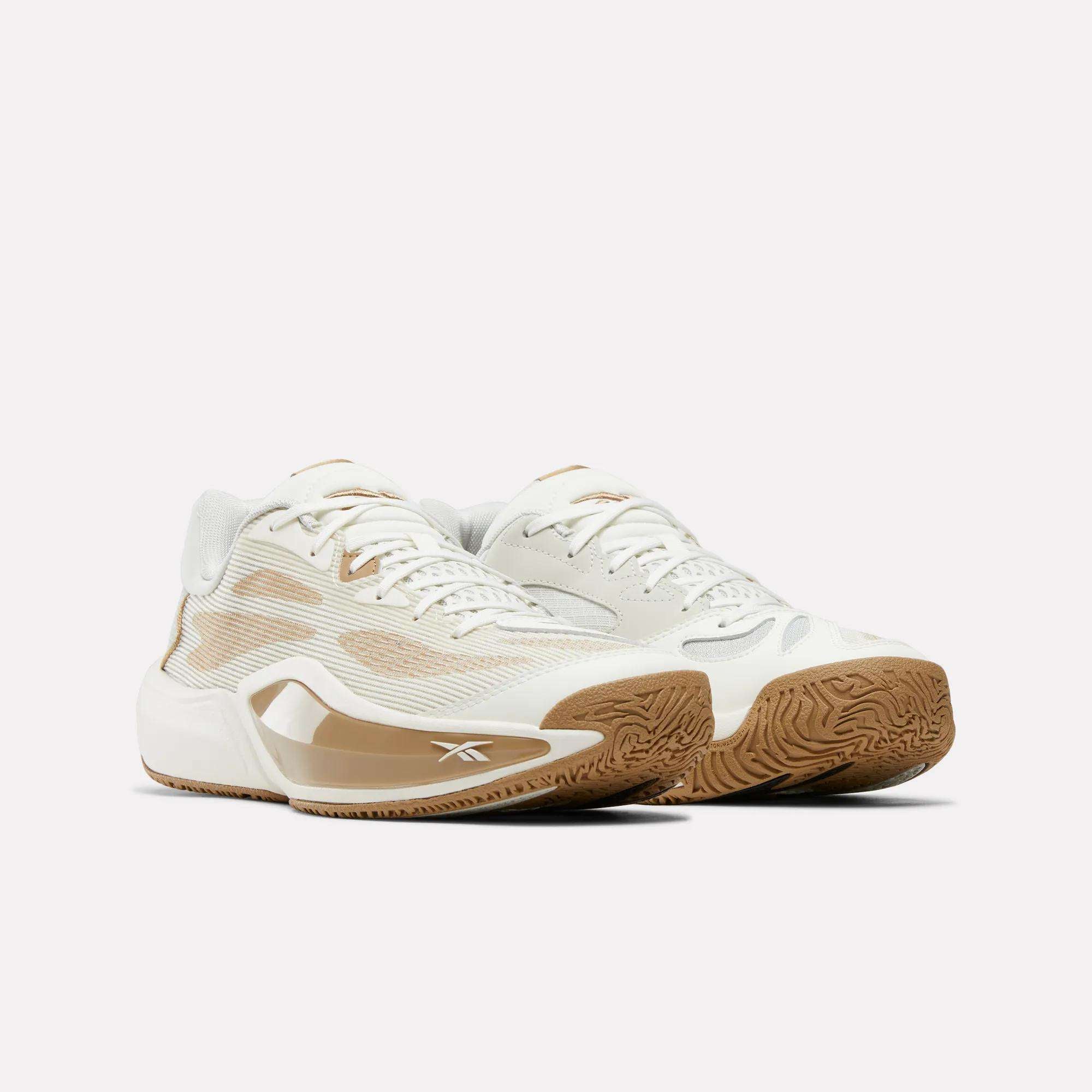 The Reebok Engine A 26 Basketball Shoes are white and tan athletic sneakers with gum soles, mesh accents, and the Reebok logo, designed for stability and energy return, shown on a plain light background.