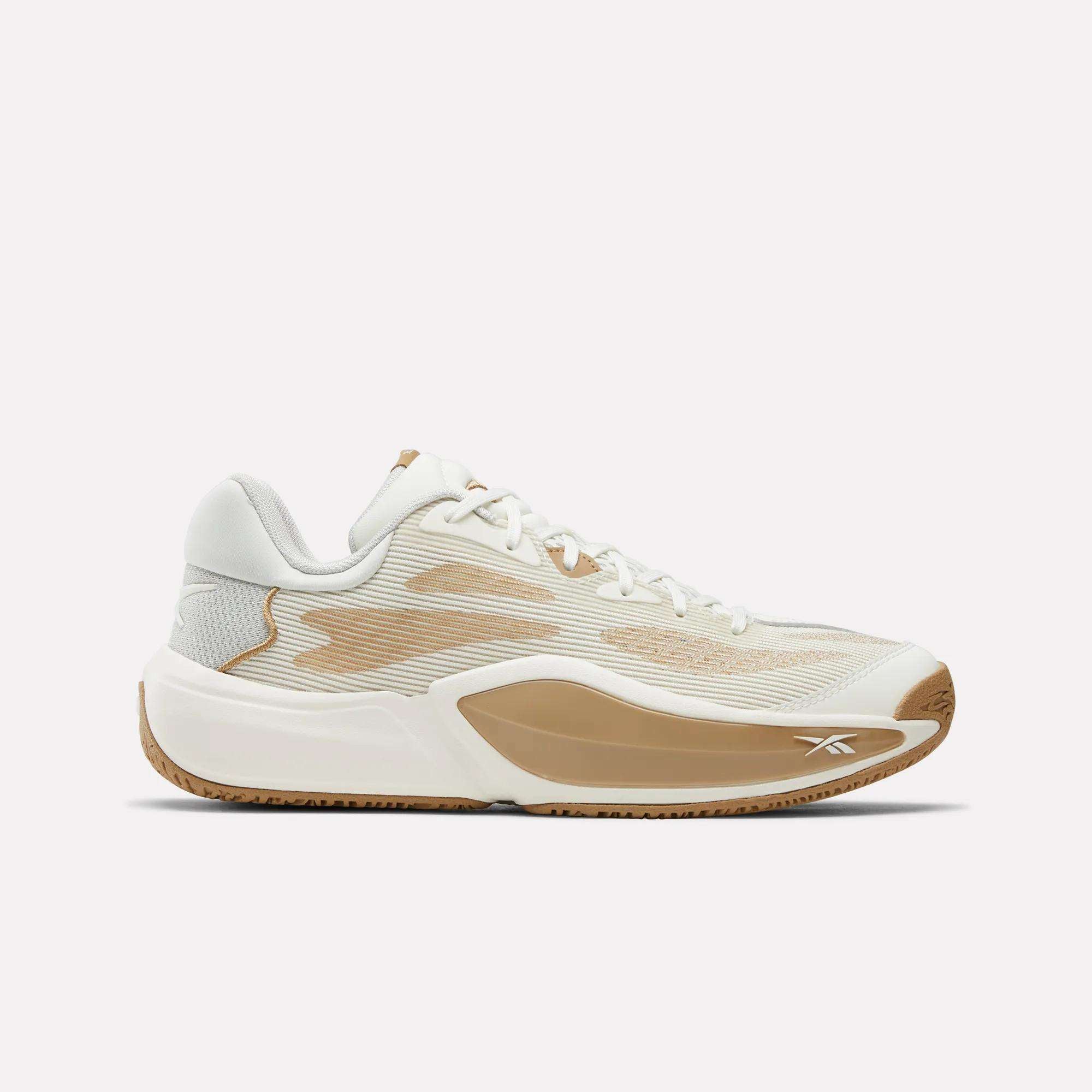 The Reebok Engine A 26 Basketball Shoes feature a white and beige low-top design with translucent mesh panels, beige accents, and a gum rubber outsole for stability. The Reebok logo is displayed near the toe on the side.