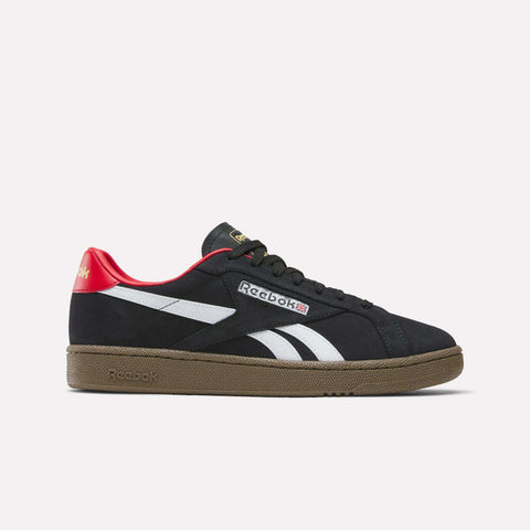 The Reebok Club C Grounds UK Shoes in black feature white side stripes, a brown sole, red heel detail, and gold tongue logo, shown in side profile on a plain white background—ideal casual sneakers with classic tennis flair.