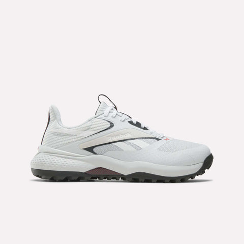 The Reebok Nano Golf Shoes are white with black and gray accents, a lightweight FlexWeave upper, mesh details, and a textured rubber sole for traction. Shown in side profile against a plain light background.