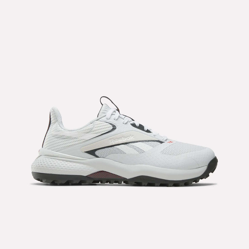 The Reebok Nano Golf Shoes are white with black and gray accents, a lightweight FlexWeave upper, mesh details, and a textured rubber sole for traction. Shown in side profile against a plain light background.
