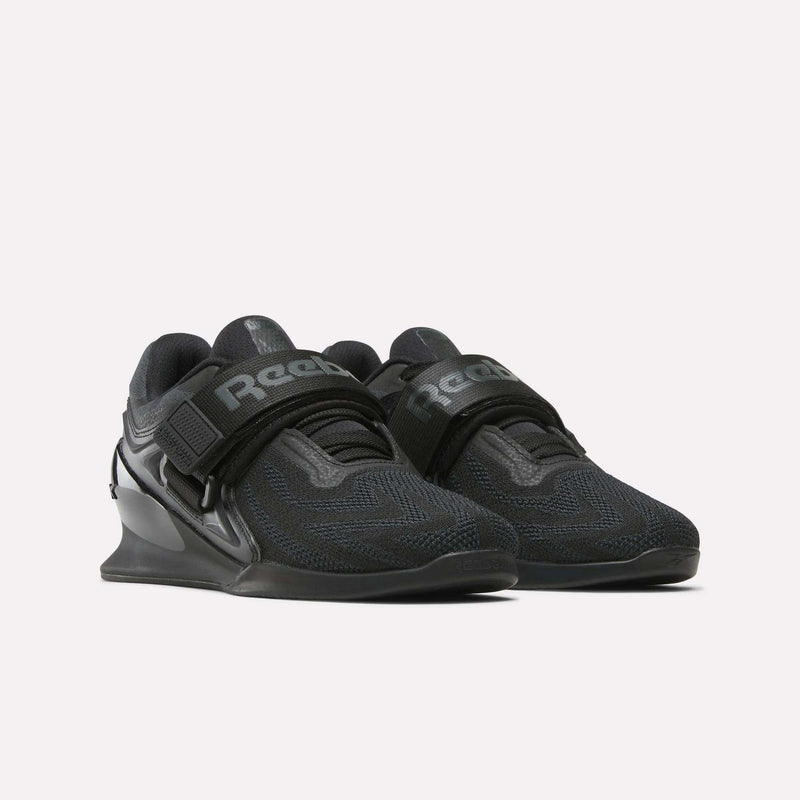 Reebok Women's Legacy Lifter IV Training Shoes in black with a mesh upper, Velcro straps, and elevated heels are shown on a white background for optimal support and stability.