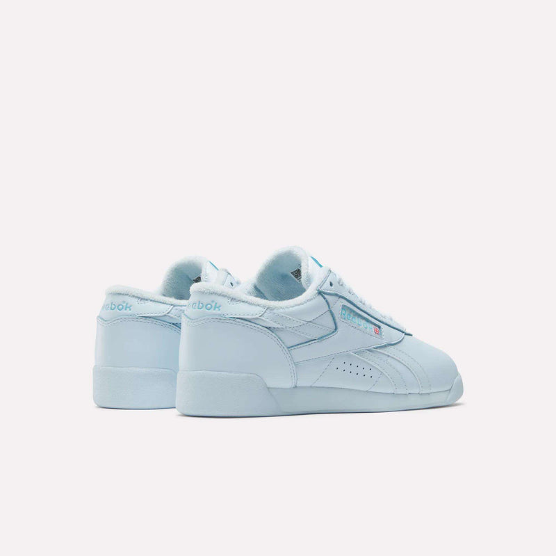 A pair of light blue Reebok Women's Freestyle Lo Shoes are shown on a white background—one facing forward, the other angled to reveal the iconic Reebok logo and branding—ideal for everyday wear.