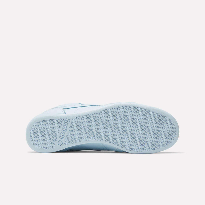 The Women's Freestyle Lo Shoes by Reebok in light blue are shown from the bottom, featuring a textured rubber sole with a hexagonal pattern and the Reebok logo embossed near the heel—ideal for everyday wear.