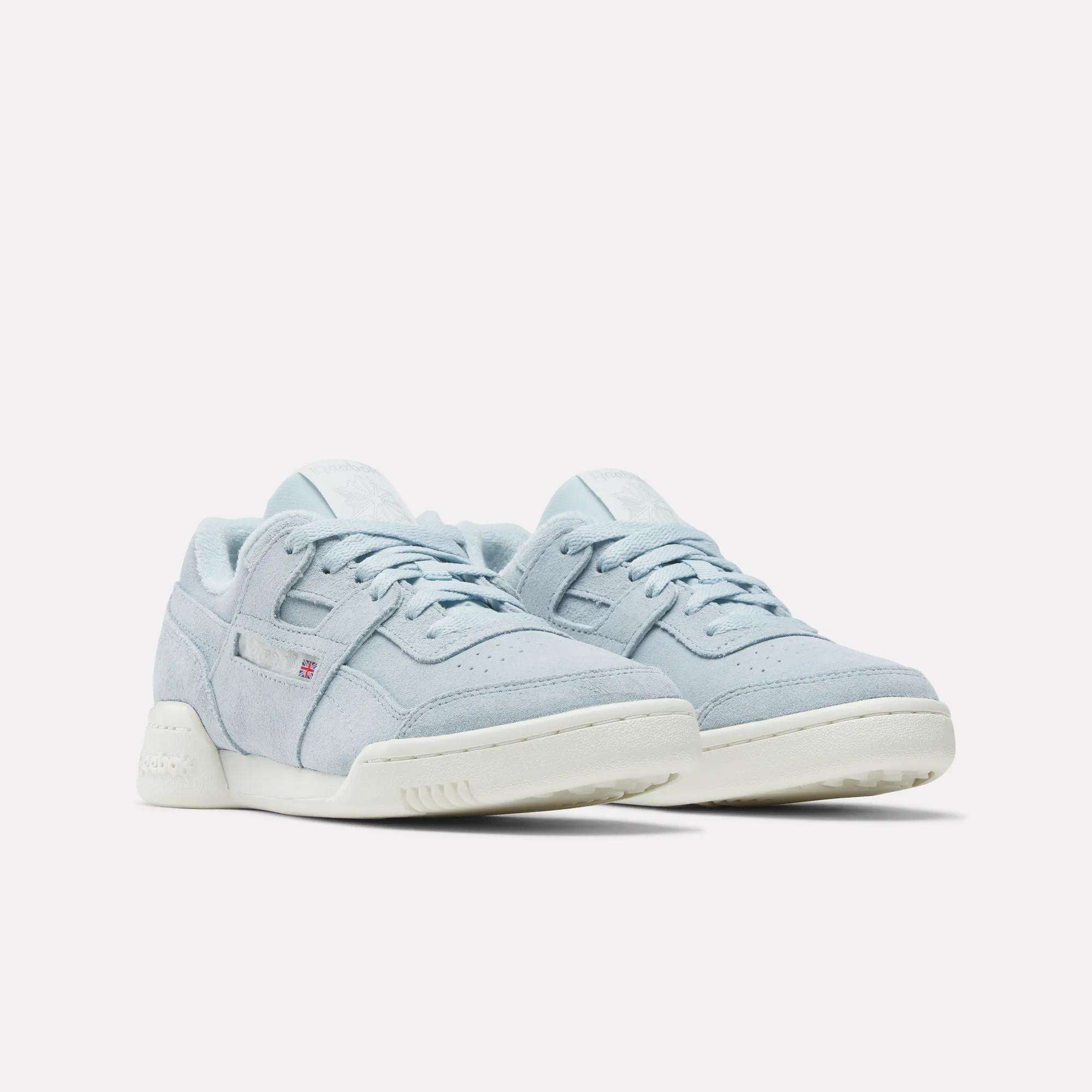 A pair of Reebok Women's Workout Plus Shoes in light blue suede with white soles, laces, and subtle side and tongue branding, nodding to classic '80s fitness style, displayed on a plain white background.