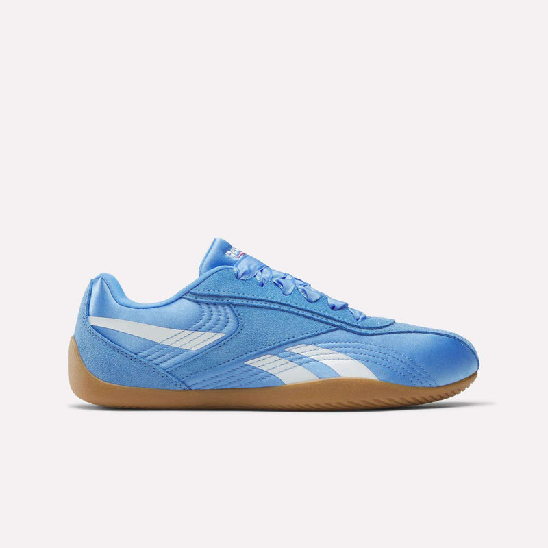 Side view of Reebok Women's Ultra Lo Shoes in blue with white stripes, a white Reebok logo, and a light brown gum sole, displayed against a plain white background.