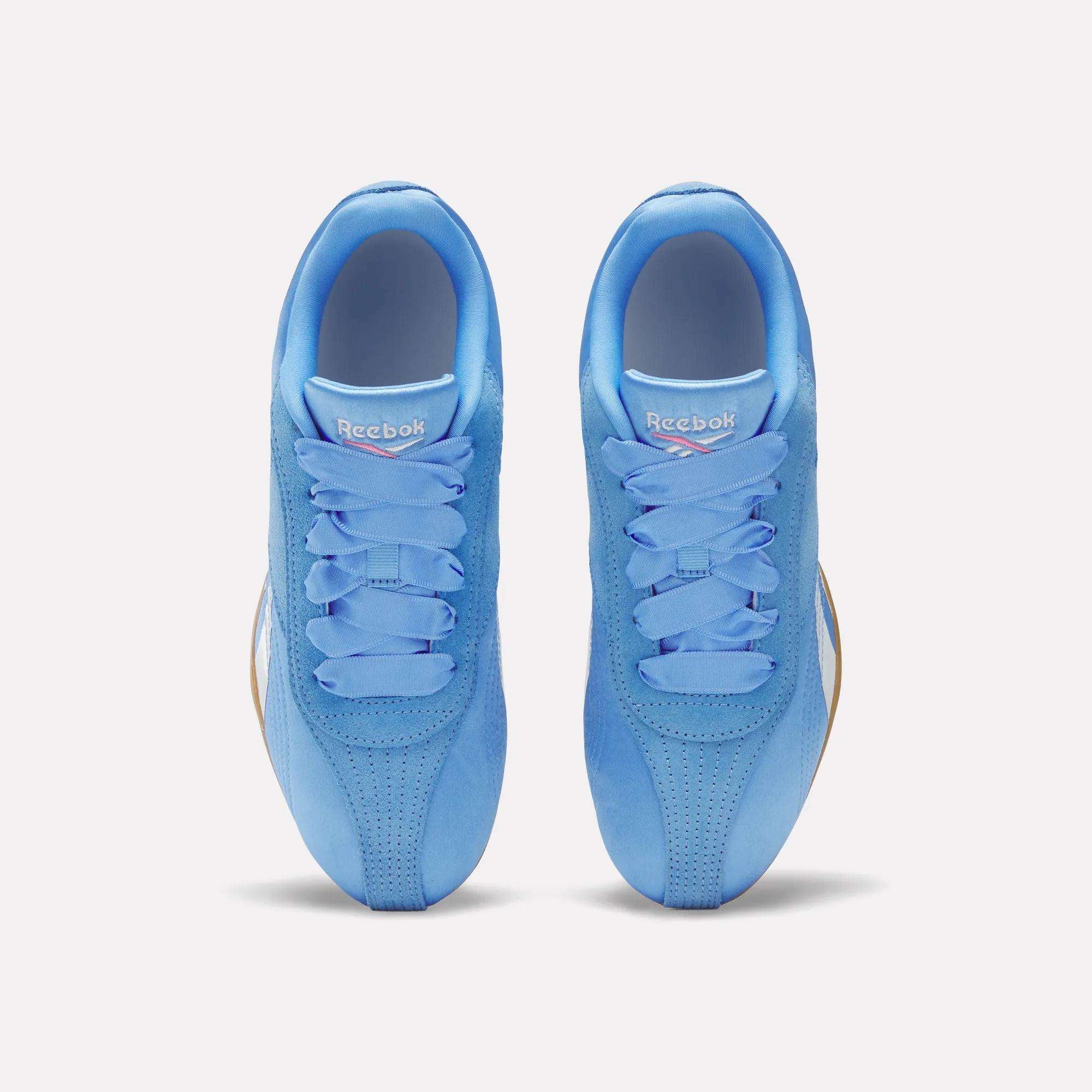 Top view of a pair of Reebok Women's Ultra Lo Shoes in bright blue with blue laces, perforated toes, and white Reebok logos on the tongues, shown side by side on a light background.