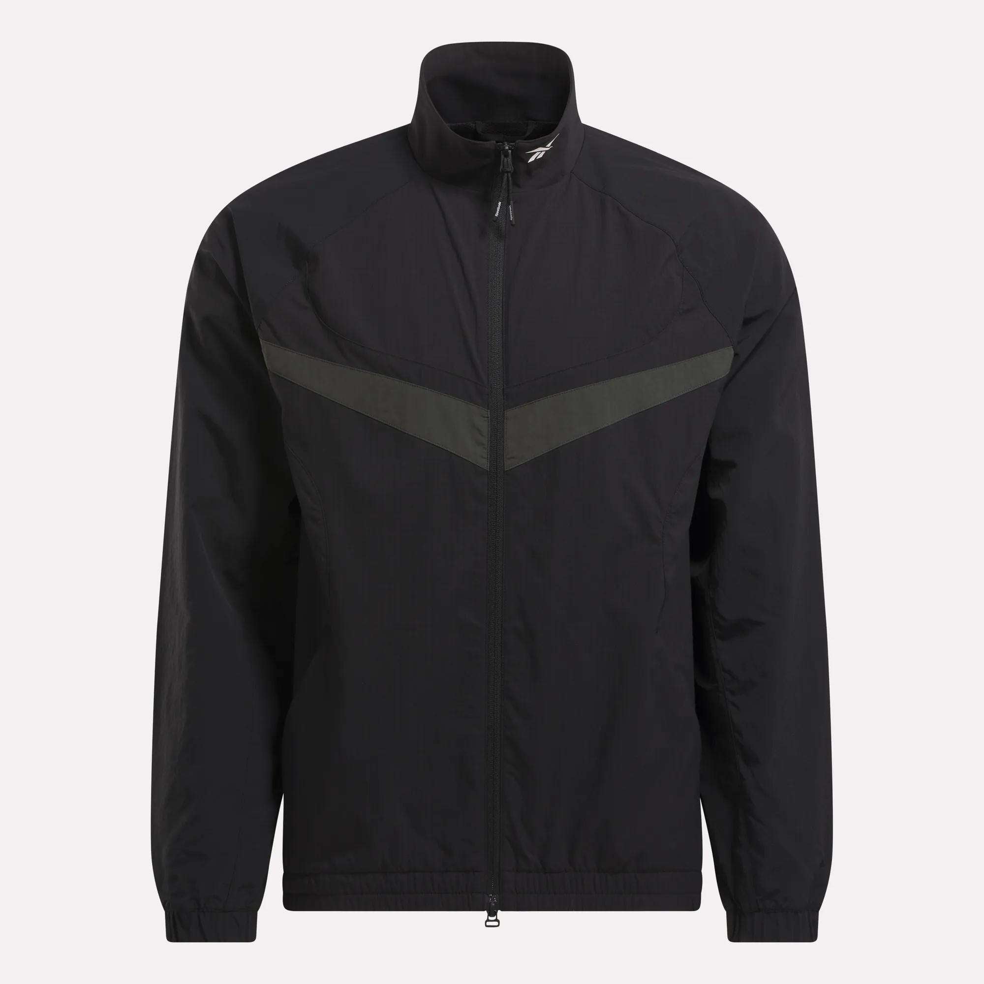 The Reebok Warm Up Track Jacket features a black zip-up design with a stand-up collar, elastic cuffs, and a subtle dark grey chevron across the chest—ideal for basketball warmups or casual wear.