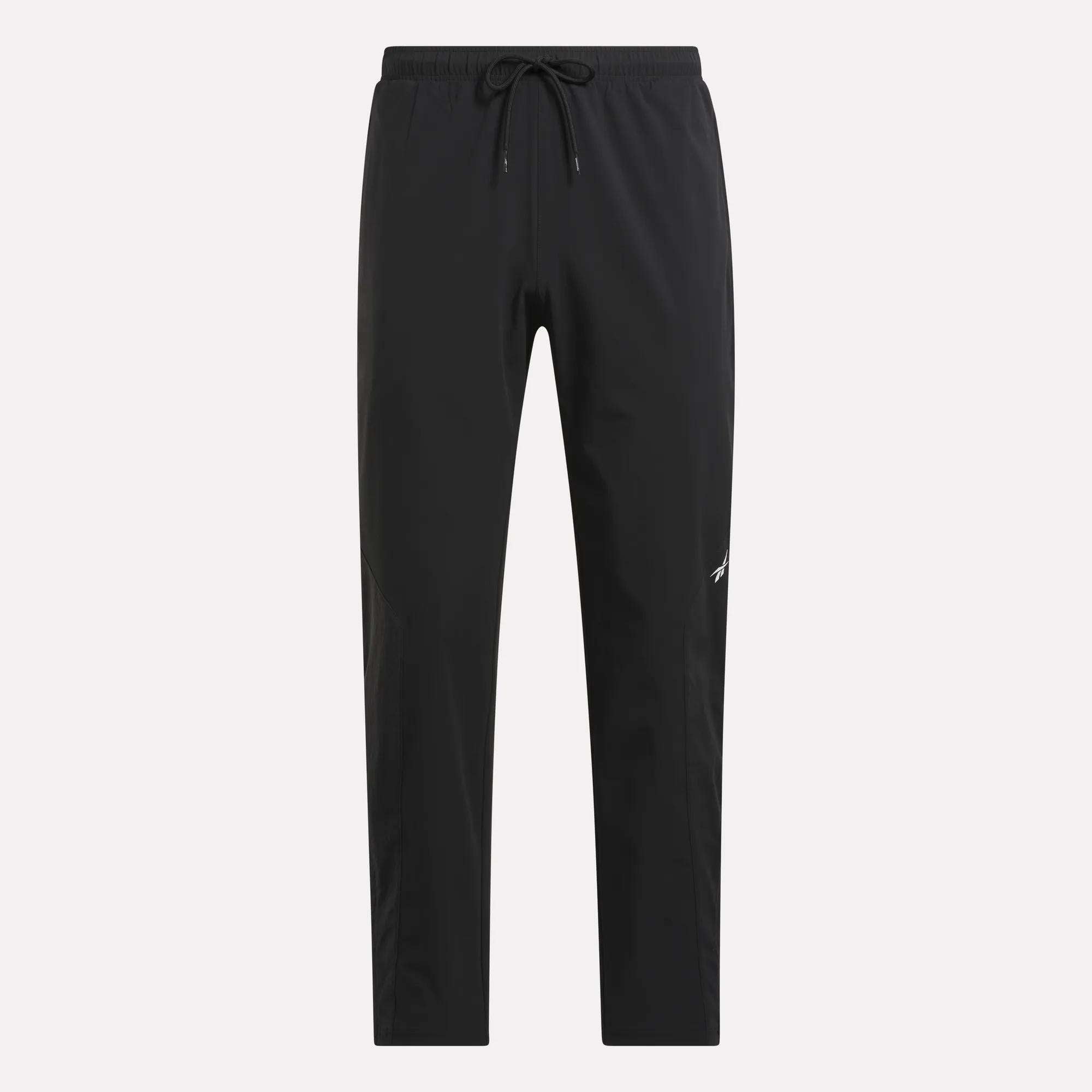 Reebok Track Pants: black athletic pants with a drawstring waist, tapered legs, and a white logo on the left thigh—ideal for basketball or workouts, shown on a plain light background.