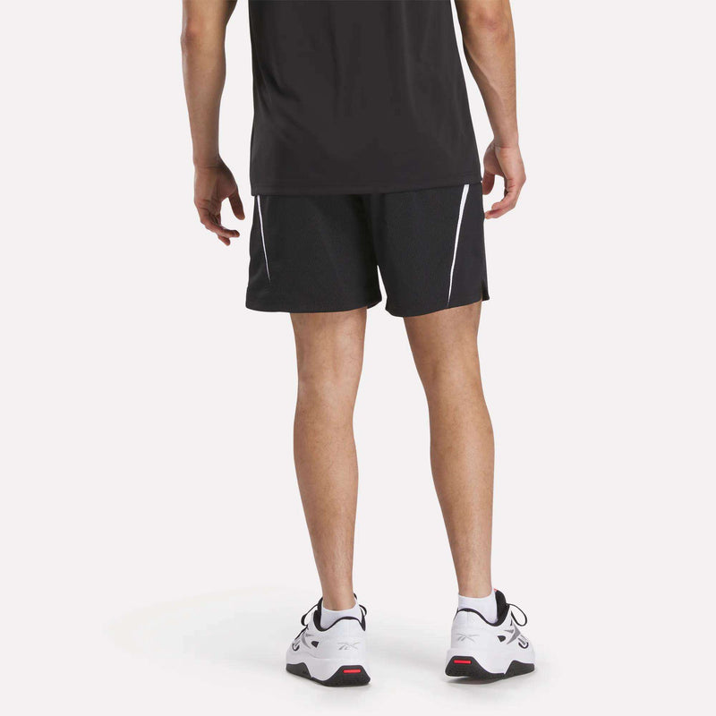 A man faces away from the camera in a black t-shirt, Reebok Mesh Shorts, and white athletic shoes with black and red details. The shorts are black with white accents and breathable mesh. The background is plain white.