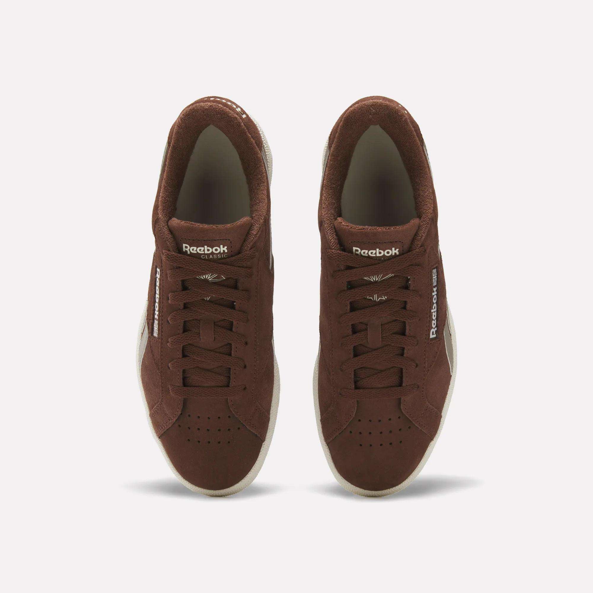 A pair of Reebok Club C Grounds UK Shoes in brown suede viewed from above, with white soles, laces, and Reebok branding on the tongue and side, delivering a classic vintage tennis style.